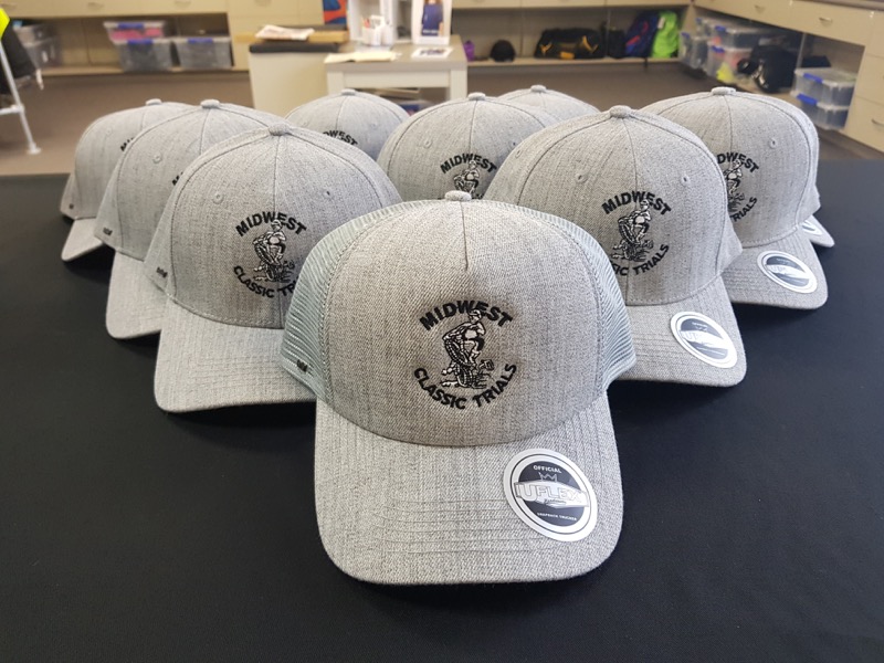 Row of grey trucker caps embroidered with the Midwest Classic Trials logo